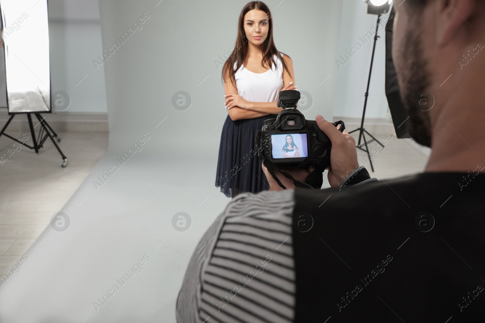 Photo of Professional photographer reviewing picture and model in studio
