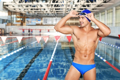 Photo of Young athletic man in cap and goggles near swimming pool