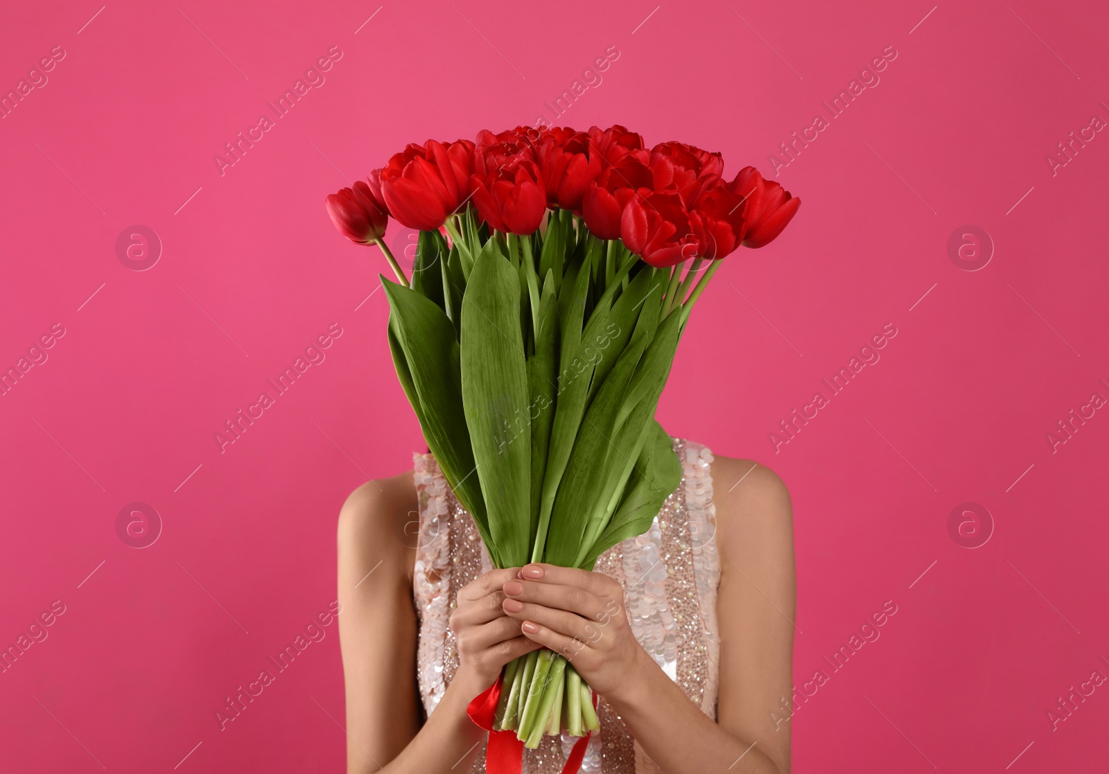 Photo of Woman with red tulip bouquet on pink background. 8th of March celebration