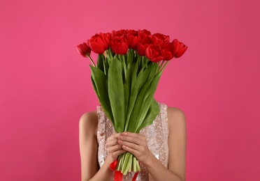 Photo of Woman with red tulip bouquet on pink background. 8th of March celebration