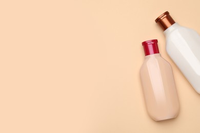 Photo of Bottles of shampoo on beige background, flat lay. Space for text