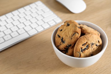 Chocolate chip cookies on wooden table at workplace. Space for text