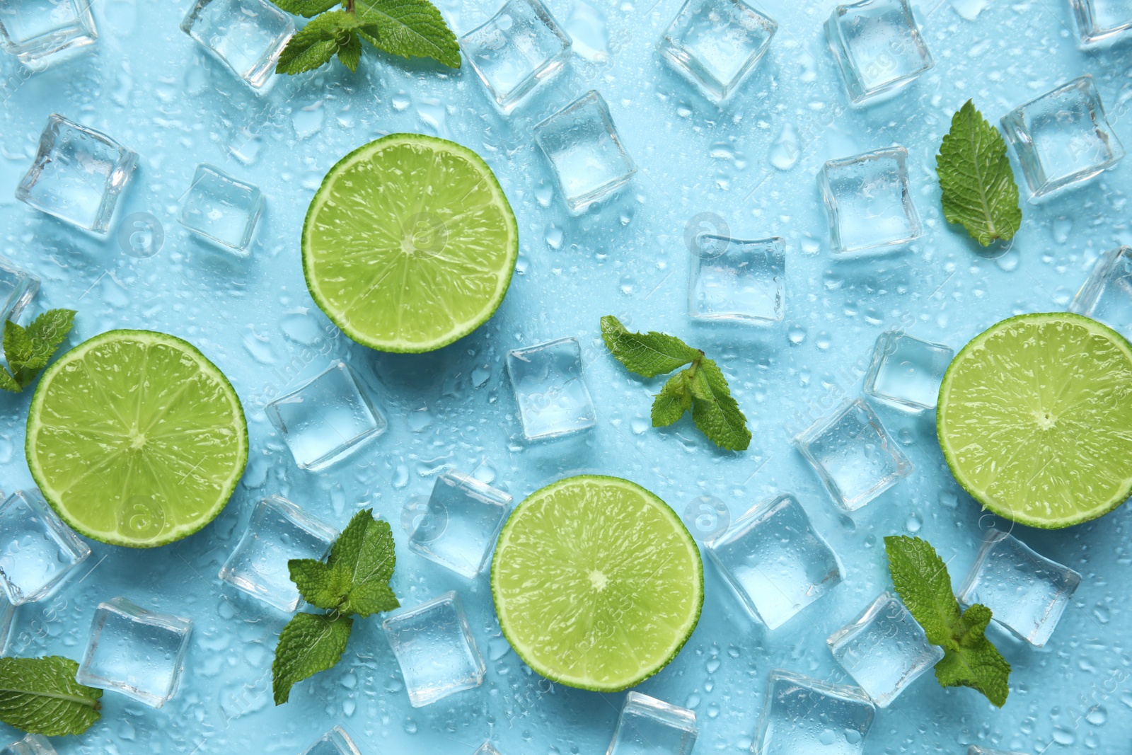 Photo of Ice cubes, mint and cut limes on turquoise background, flat lay. Ingredients for refreshing drink