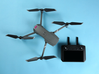 Modern drone with controller on blue background, flat lay