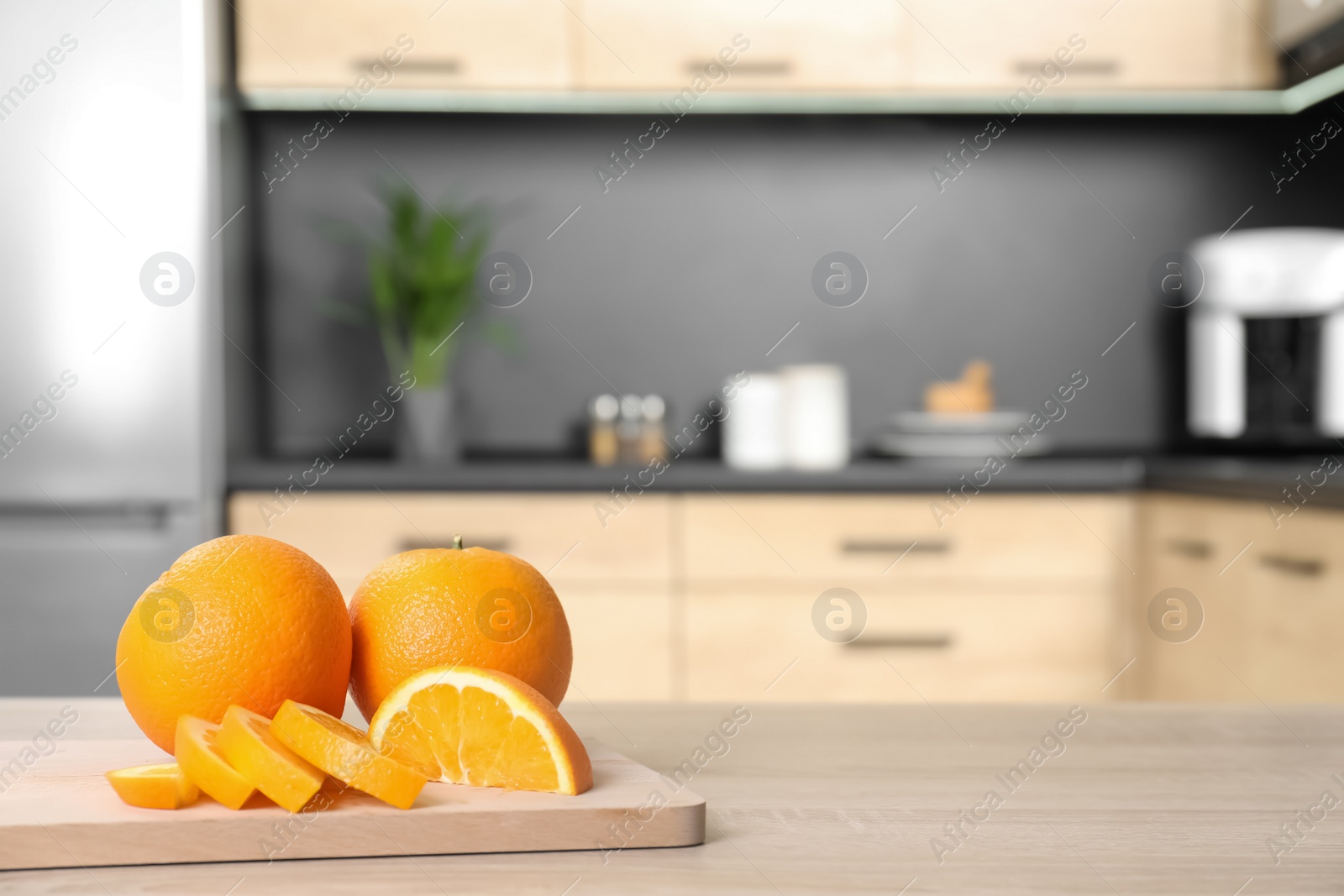 Photo of Fresh oranges on wooden table in kitchen. Space for text