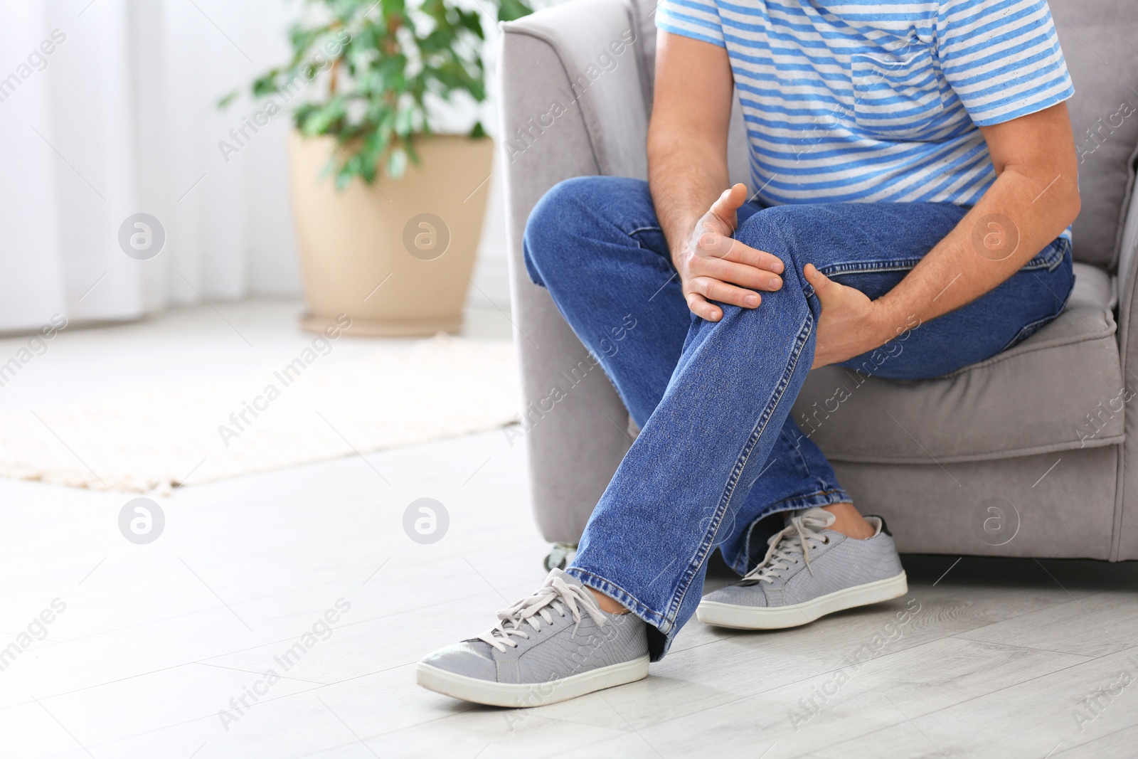 Photo of Senior man suffering from knee pain at home, closeup. Space for text