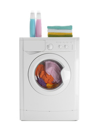 Modern washing machine with laundry, stack of towels and detergents on white background