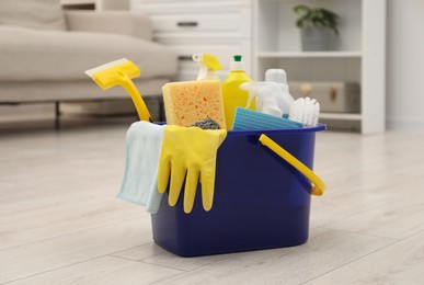 Different cleaning supplies in bucket on floor at home