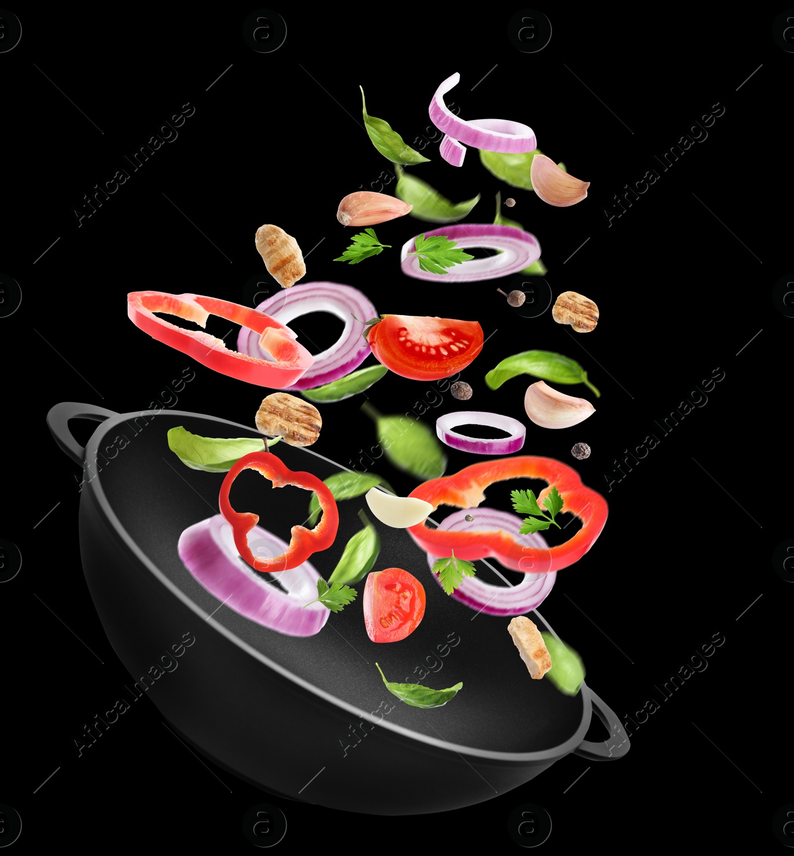 Image of Different tasty ingredients falling into wok on black background