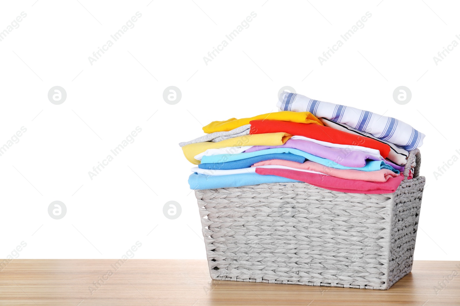 Photo of Basket with clean laundry on wooden table, white background