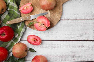 Tasty apples with red pulp and leaves on white wooden table, flat lay. Space for text