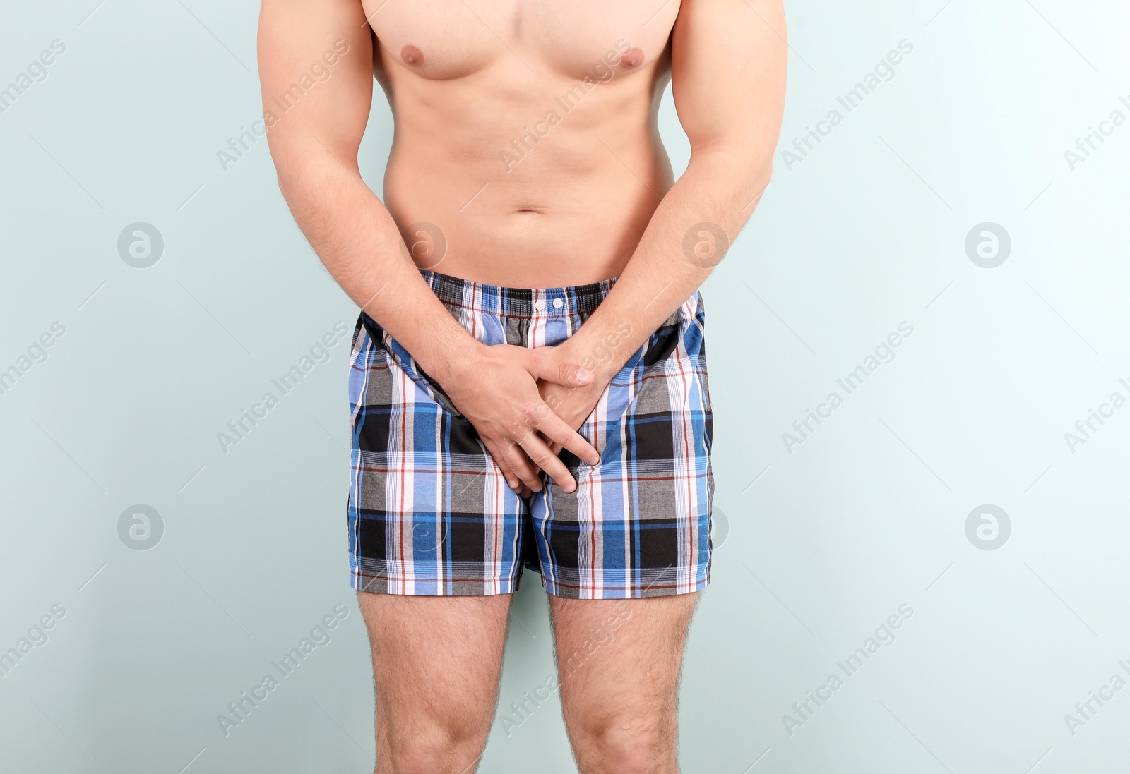 Photo of Young man with urological problems suffering from pain on color background