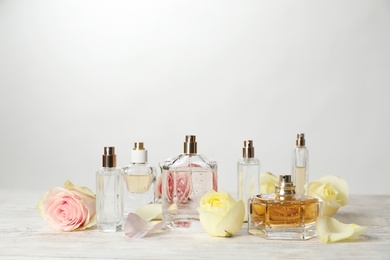 Bottles of perfume and flowers on table against light background