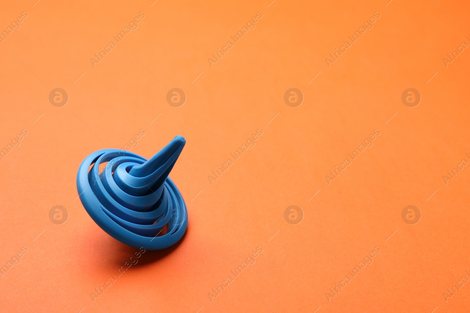 Photo of One blue spinning top on orange background