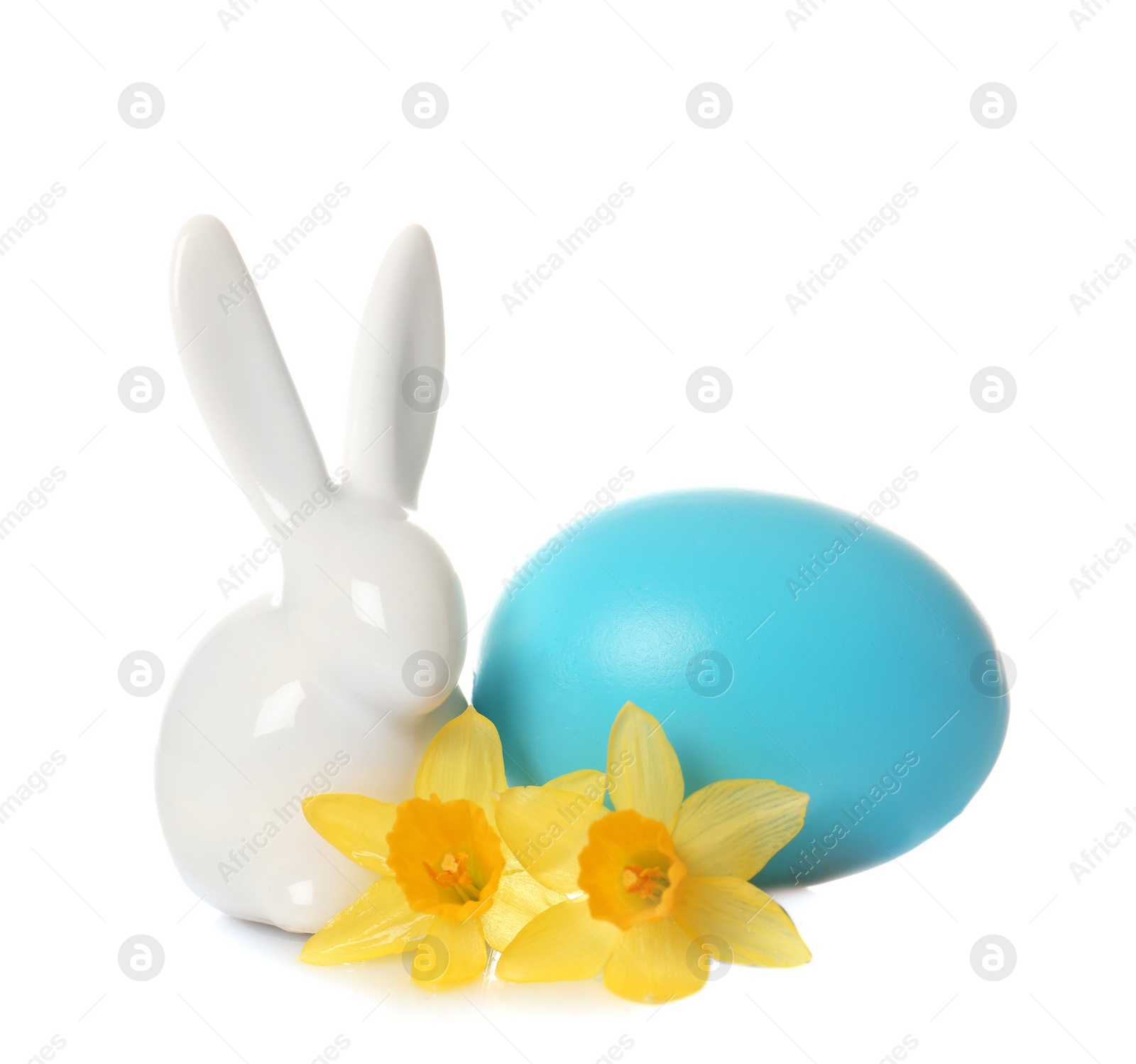 Photo of Cute ceramic Easter bunny with flower and dyed egg on white background