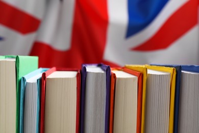 Photo of Learning foreign language. Different books against flag of United Kingdom, closeup