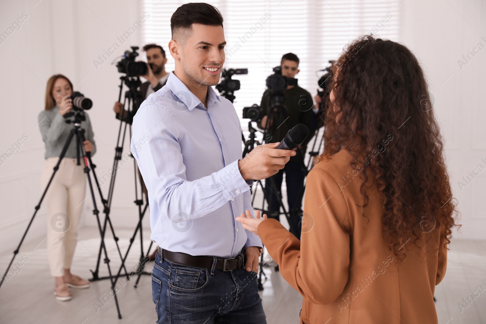 Photo of Professional journalist interviewing young African American woman indoors