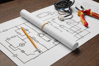 Photo of Wiring diagram, pencil, wires and pliers on wooden table