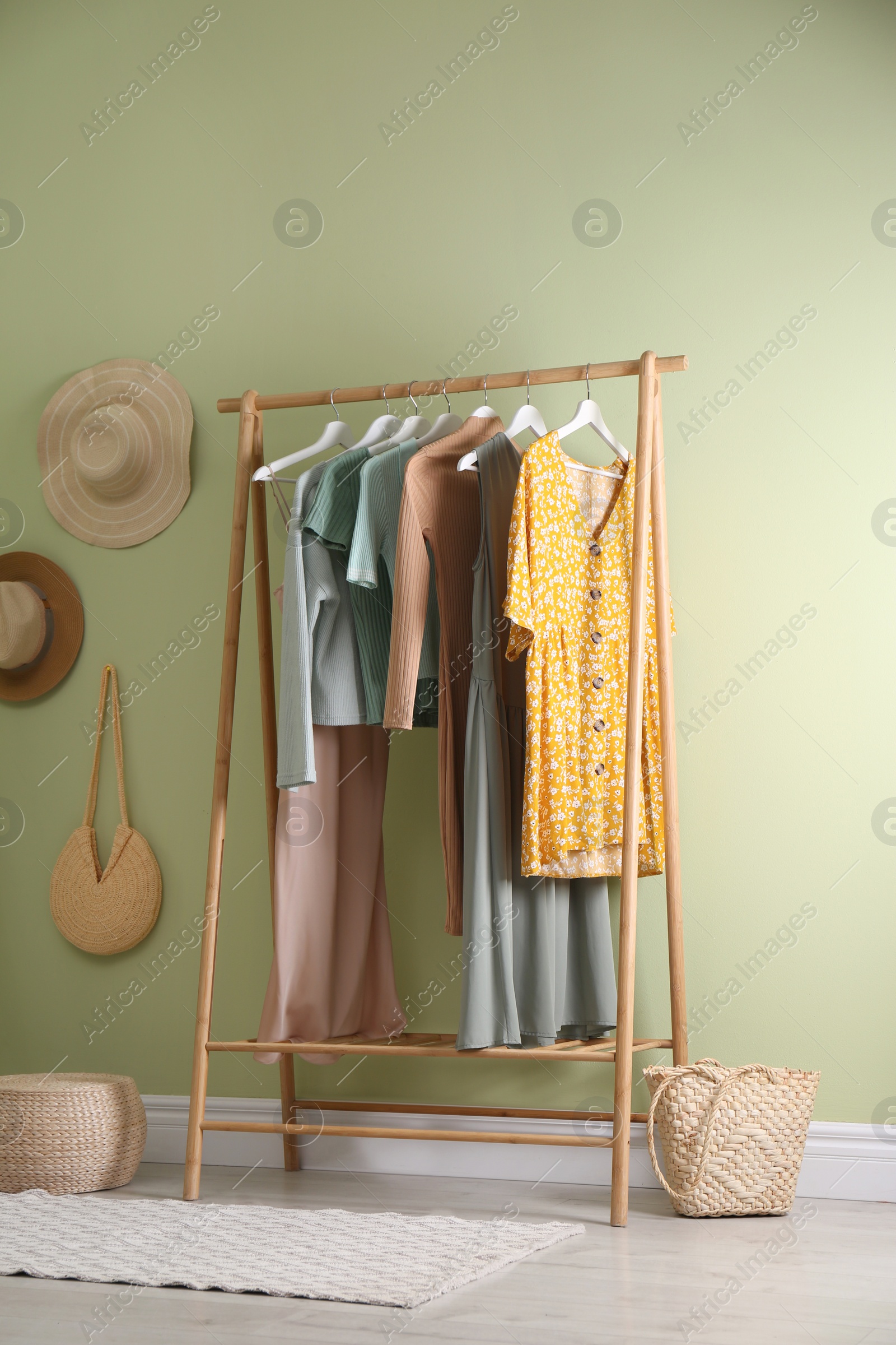 Photo of Clothing rack near light green wall in dressing room. Interior design