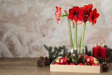 Beautiful red amaryllis flowers and Christmas decor on wooden table. Space for text