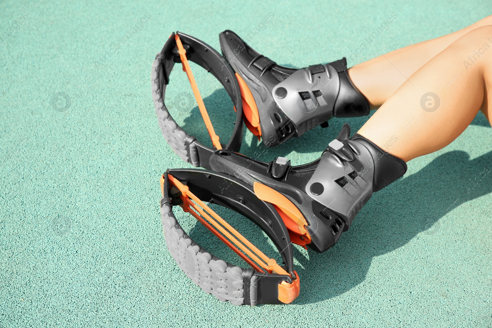 Photo of Woman with kangoo jumping boots on turquoise textured background, closeup