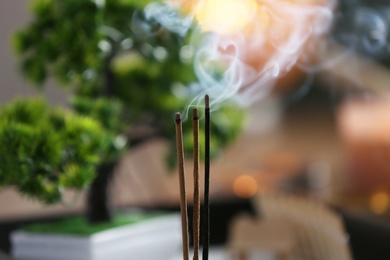 Incense sticks smoldering on blurred background, closeup