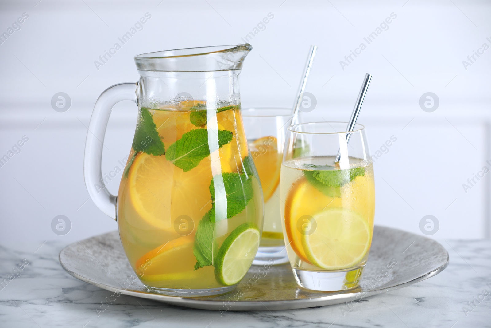 Photo of Freshly made lemonade with mint in jug and glasses on white marble table