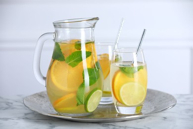 Freshly made lemonade with mint in jug and glasses on white marble table