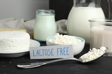 Photo of Many different dairy products and card with phrase Lactose free on black textured table, closeup