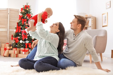 Happy couple with baby celebrating Christmas together at home