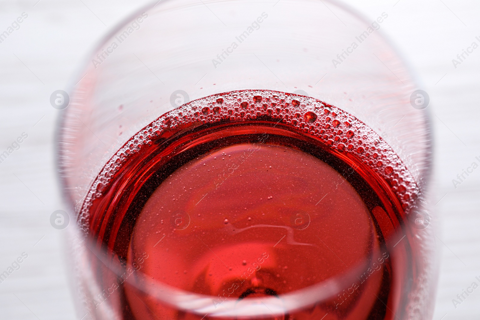 Photo of Glass of delicious rose wine on white table, closeup
