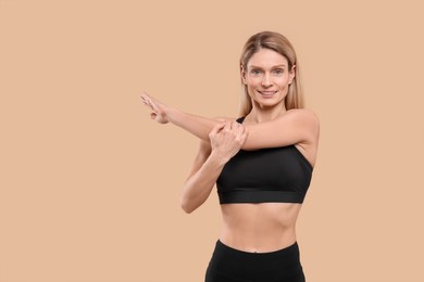 Athletic woman stretching on beige background, space for text