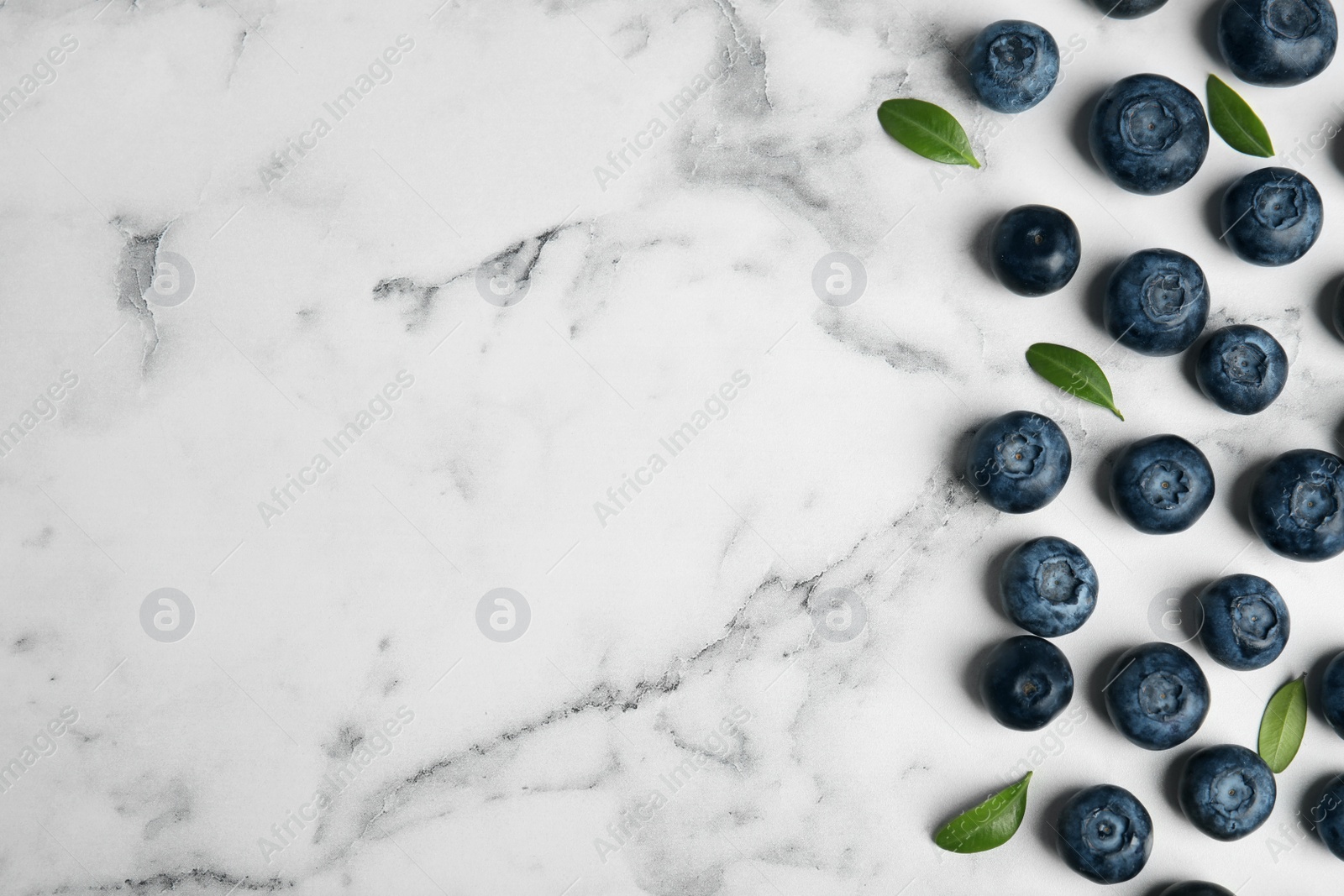 Photo of Tasty fresh blueberries and leaves on marble table, flat lay with space for text