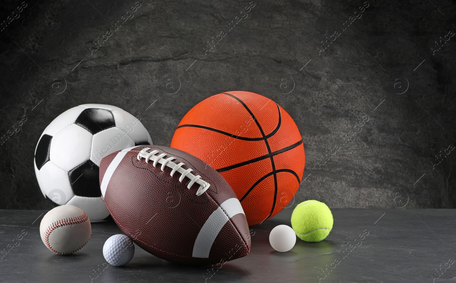 Photo of Many different sports balls on dark gray background, space for text