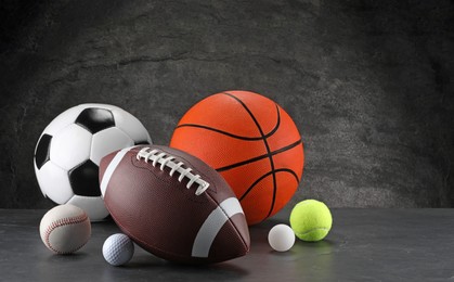 Photo of Many different sports balls on dark gray background, space for text