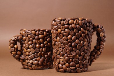 Cups made of coffee beans on brown background, closeup