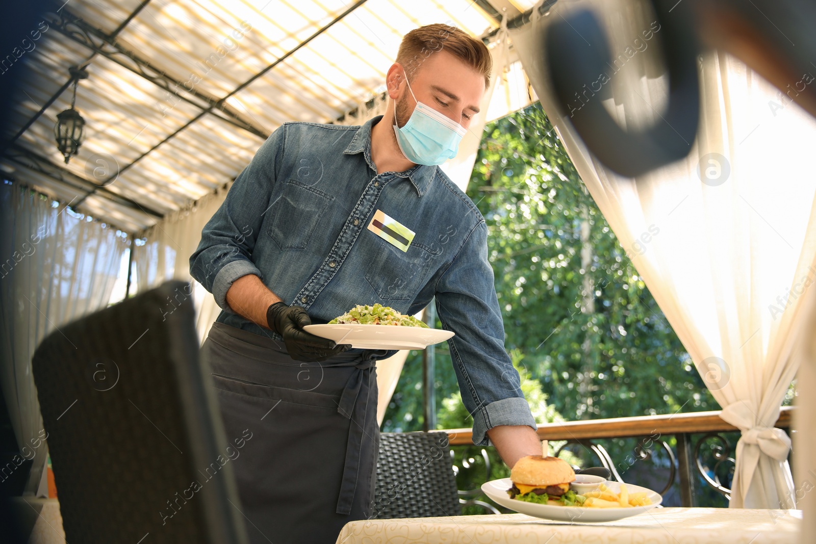 Photo of Waiter serving food in restaurant. Catering during coronavirus quarantine