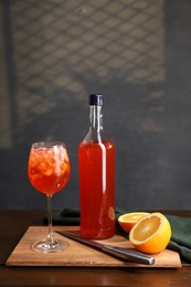 Photo of Aperol spritz cocktail and ice cubes in glass and bottle on wooden table