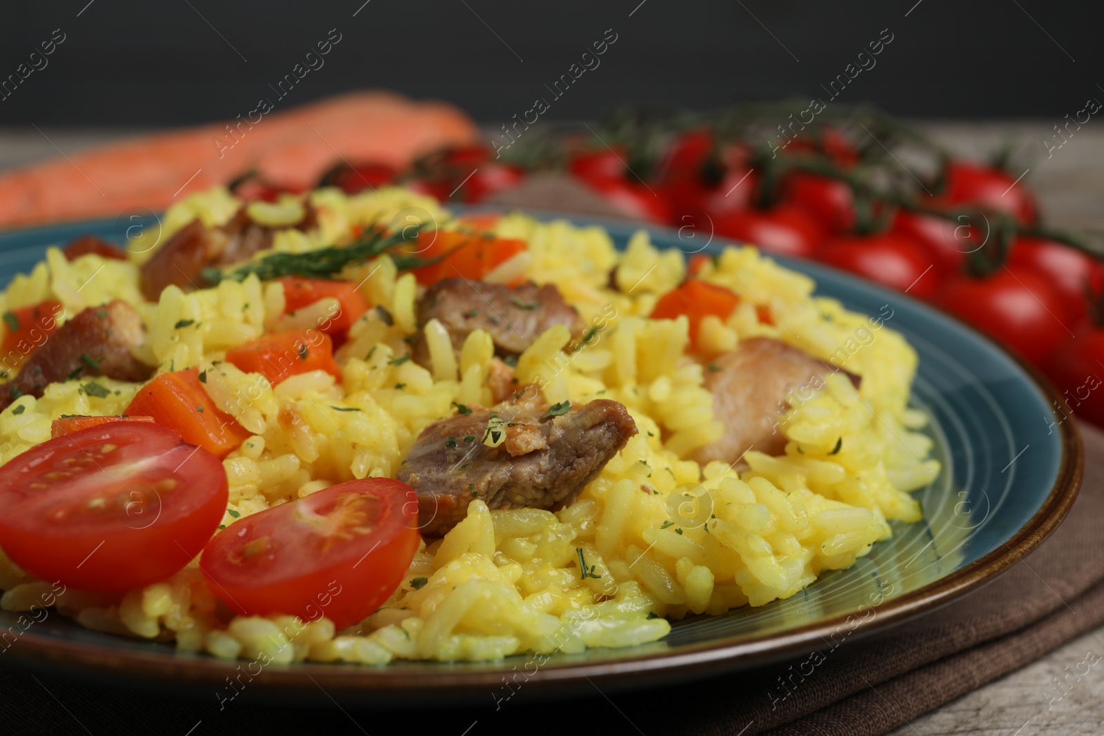 Photo of Delicious pilaf with meat and tomatoes on plate, closeup