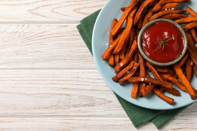 Delicious sweet potato fries served with sauce on white wooden table, top view. Space for text