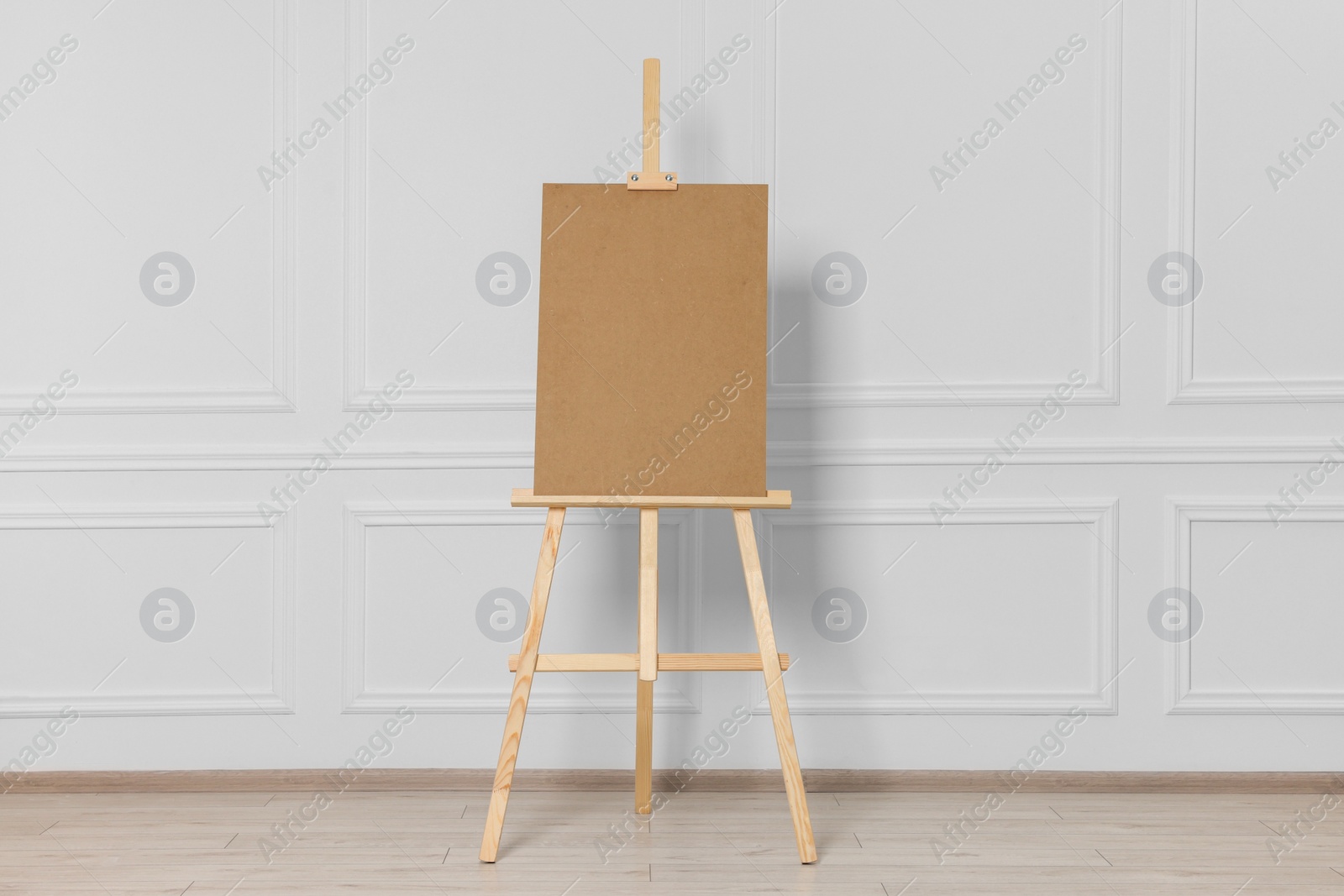 Photo of Wooden easel with blank board near white wall indoors