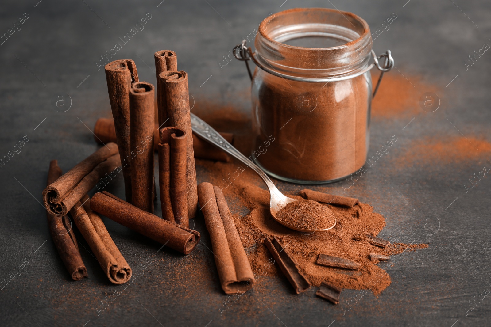 Photo of Composition with aromatic cinnamon powder and sticks on grey background