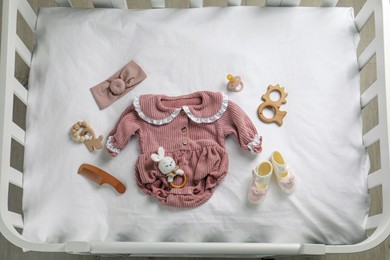 Photo of Flat lay composition with cute baby clothes and accessories on white bedsheet in crib