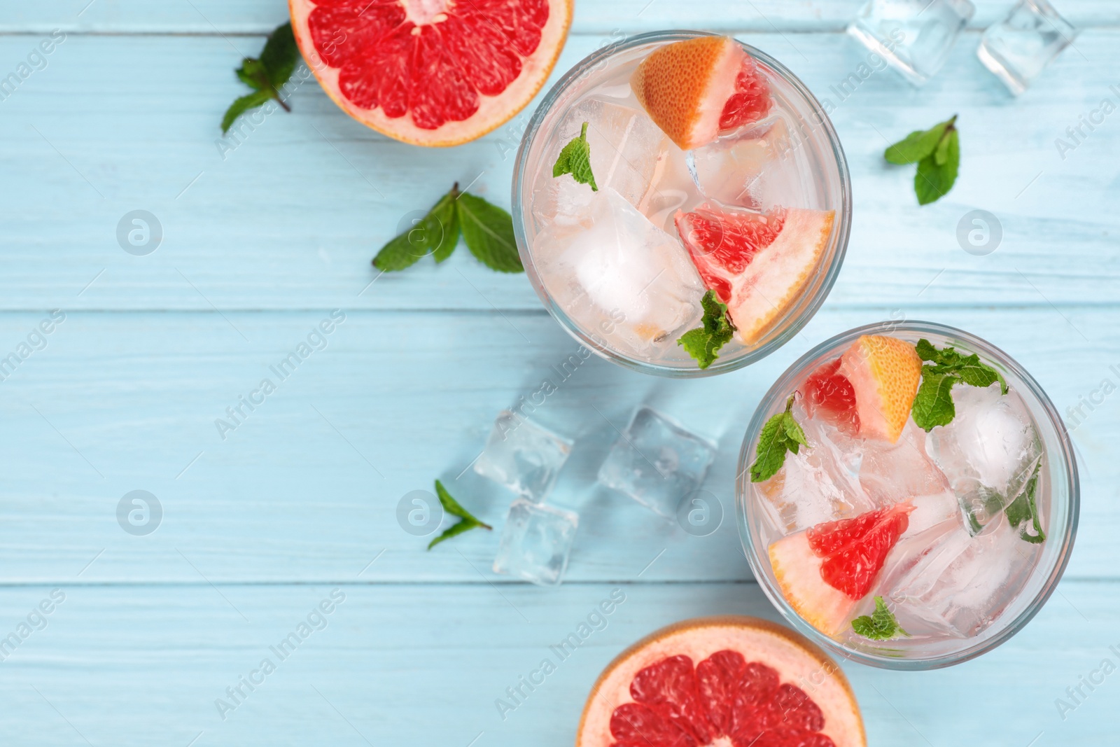 Photo of Flat lay composition of refreshing drink and grapefruits on light blue wooden table