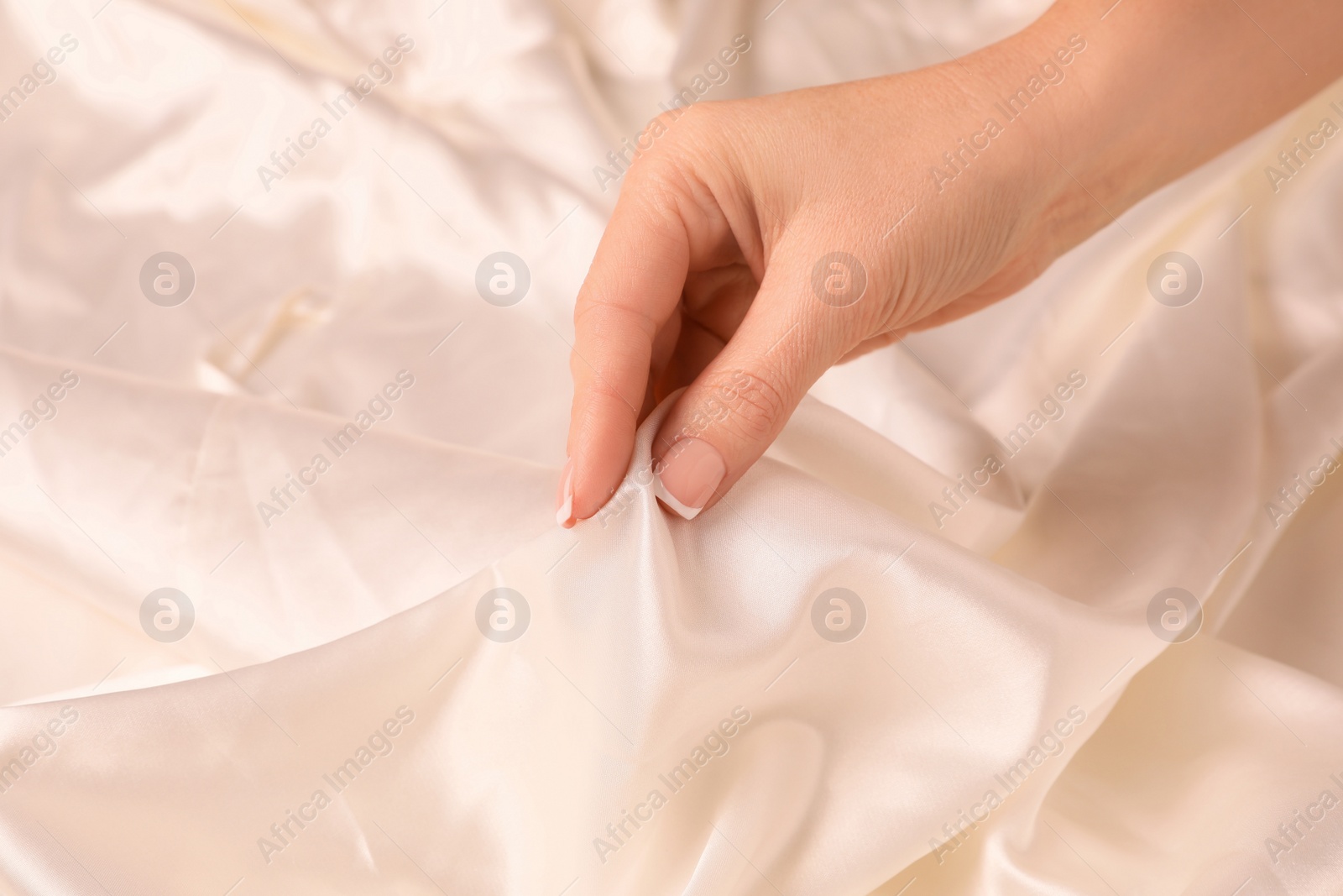 Photo of Woman touching smooth silky white fabric, closeup view