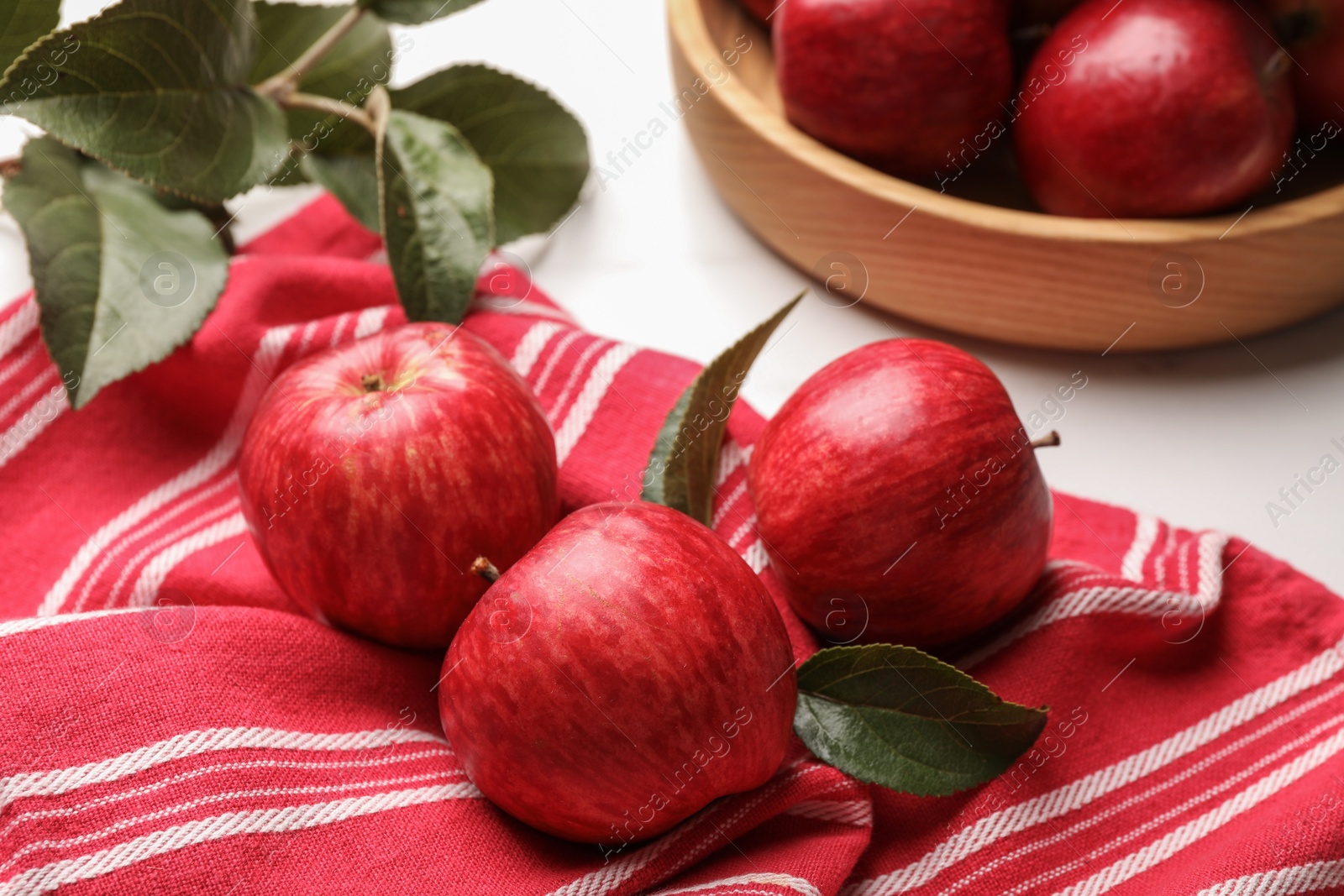 Photo of Fresh red apples with leaves on white table