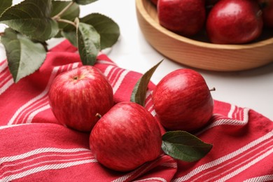 Fresh red apples with leaves on white table