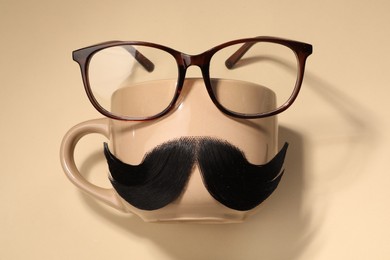 Photo of Artificial moustache, cup and glasses on beige background, top view