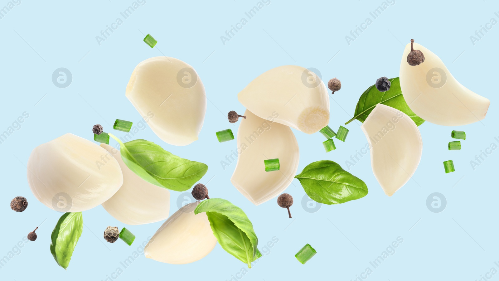 Image of Fresh peeled garlic cloves, peppercorns and basil flying on light blue background