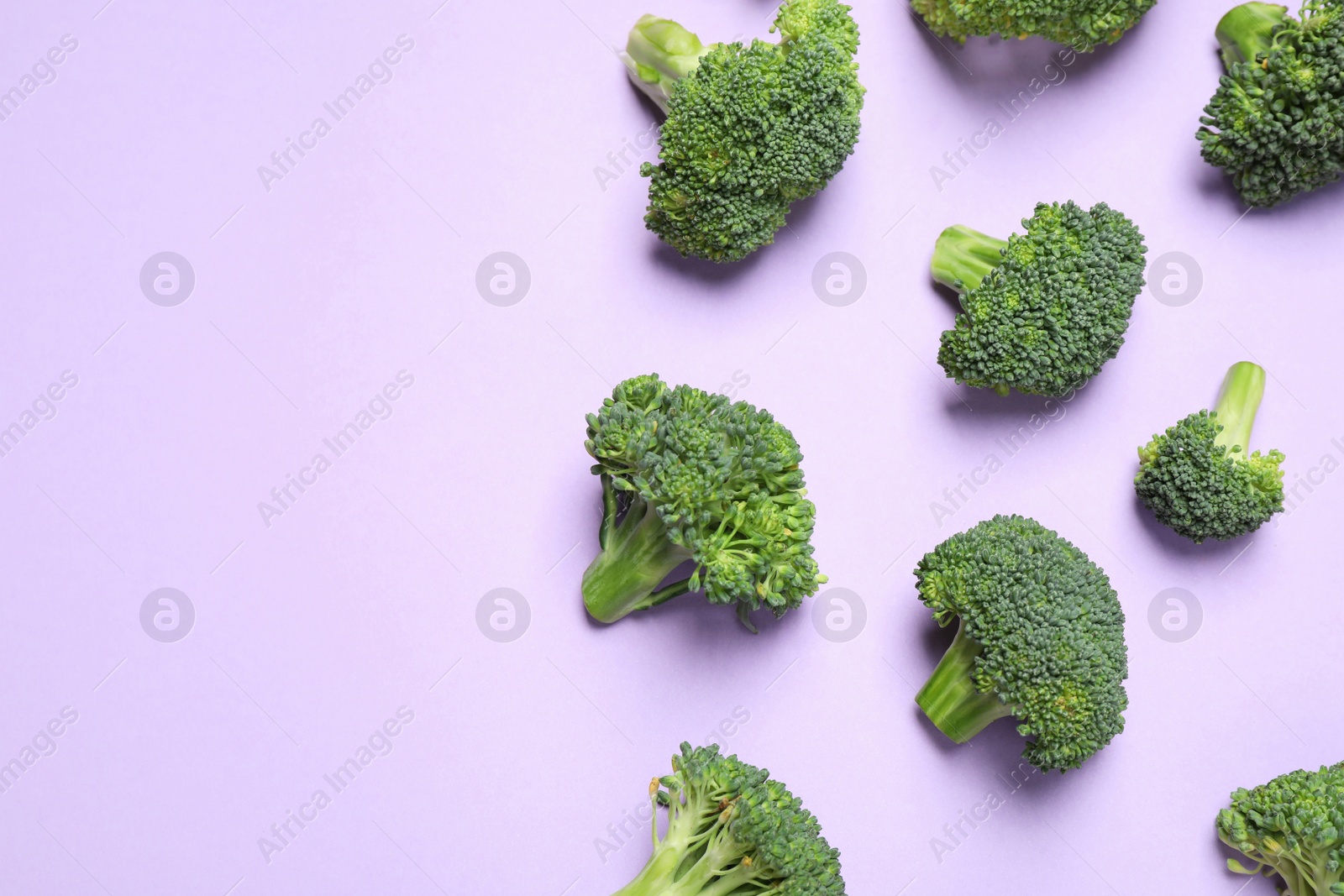 Photo of Fresh tasty broccoli on violet background, flat lay. Space for text